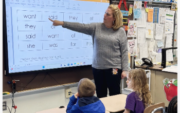 Teacher points to smart board in classroom